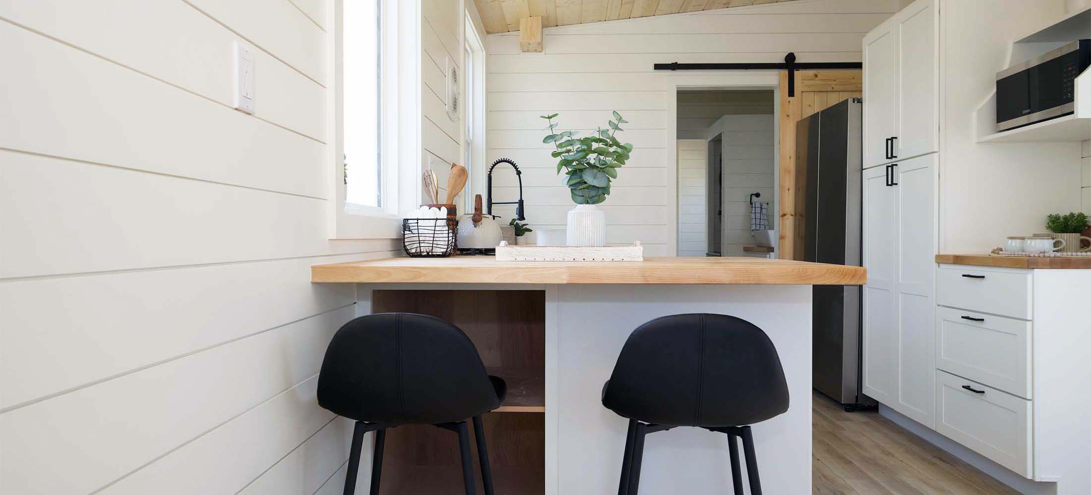 Kingdom 360 kitchen. Modern bar stools fit under counter for casual dining or extra seating in this tiny home. 